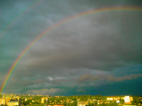 City landscape after a thunderstorm. Double rainbow over the city after a thunderstorm against a dark sky.