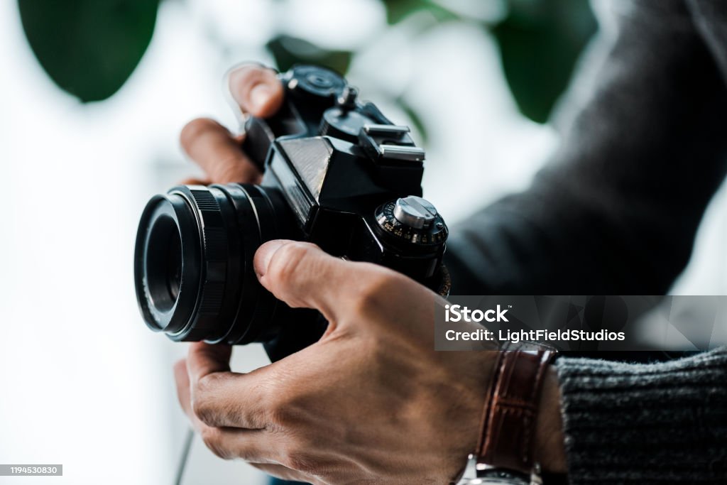 abgeschnittene Ansicht von bi-rassischen Mann hält Digitalkamera in Wohnung - Lizenzfrei Fotograf Stock-Foto