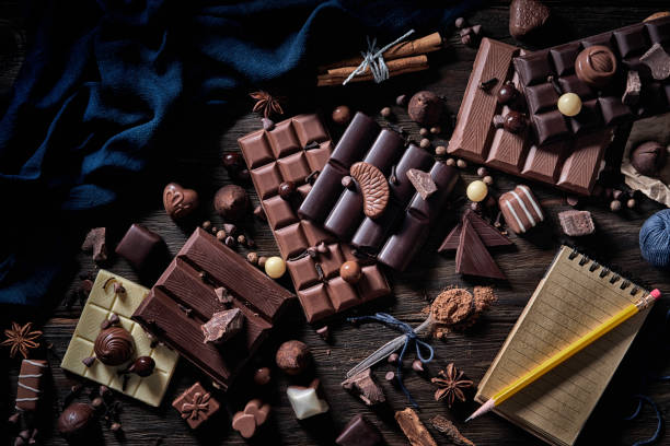 istock Low key image of assorted chocolate with a note pad and pencil old fashioned style on a wooden rustic table 1194533752
