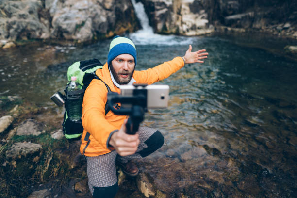 Backpacker hiking and vlogging Young man in the mountain vlogging nature and landscapes camera stock pictures, royalty-free photos & images