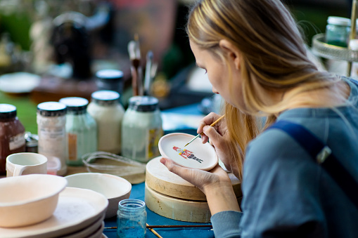 Young female artist painting Xmas decoration on handmade ceramics