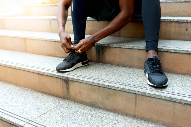 istock Athlete during running tying shoelaces on sneakers on stairway, jogger training and doing workout in downtown city. 1194539604