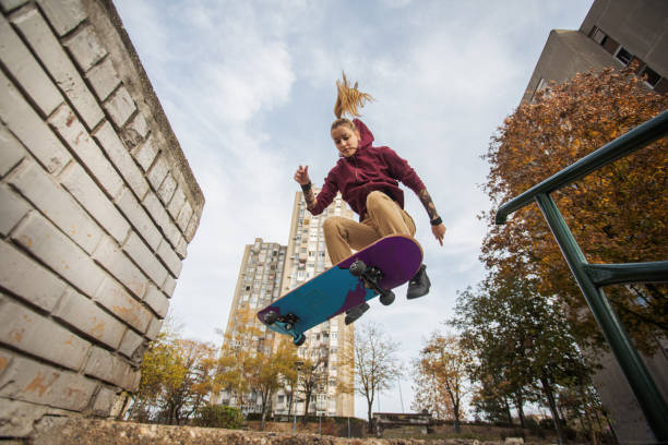 skater-frau springt auf ihrem skate. - city life urban scene skateboarding skateboard stock-fotos und bilder