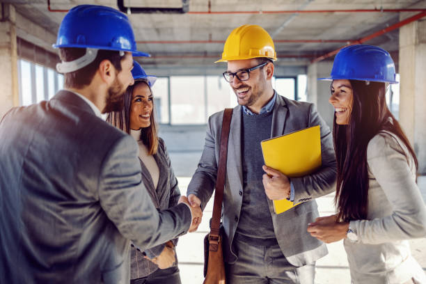 istock Smiling successful architect holding folder with contract in hands and shaking hands with businessman. Next to him are his female colleagues. 1194554462