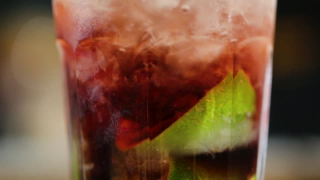 Close up of alcoholic cocktail drink with ice and lime in it on the bar counter ready to drink