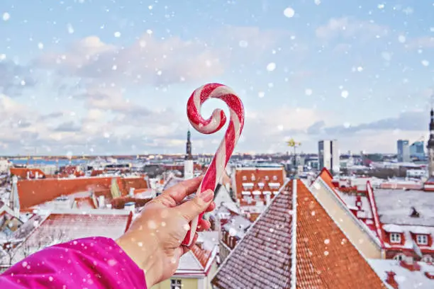 Photo of Striped candy cane lollipop in hand against old city of Tallinn