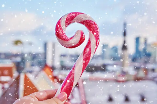 Photo of Striped candy cane lollipop in hand against old city of Tallinn