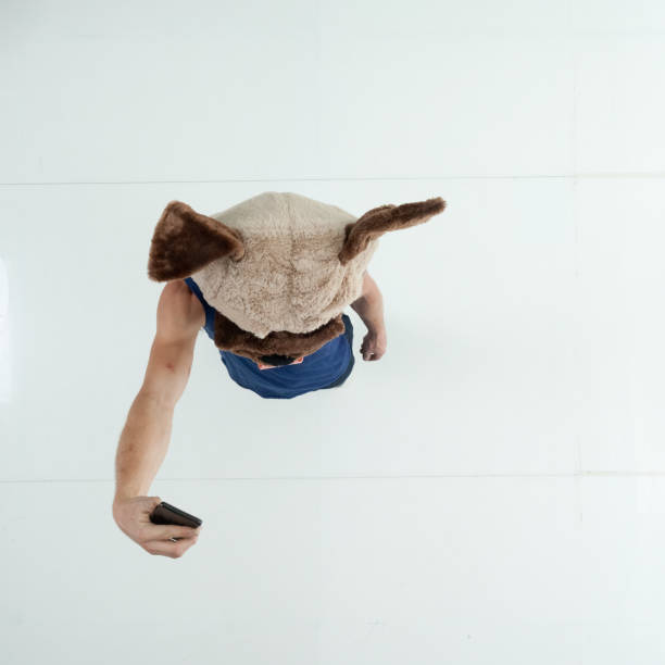 Full length / one man only / one person / directly above view / aerial view of 20-29 years old adult handsome people caucasian male / young men photography / sleeveless standing in front of white background wearing mask - disguise / costume / dog suit / tank top who is humor who is taking a selfie / photographing and holding mobile phone / using smart phone / dog longitud completa / un hombre solamente / una persona / directamente por encima de la vista / vista aérea de 20-29 años de edad adulto guapo personas caucásicas hombre / hombres jóvenes fotografía / sin mangas de pie frente a fondo blanco que es el hu
