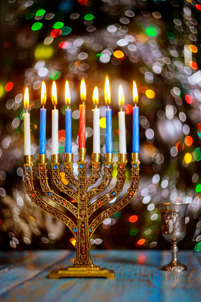 istock Hanukkah table with menorah and burning candles on sparkle background with defocused colored lights. 1194565557