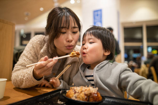 Young mother and her little son blowing to Takoyaki before eating, Young mother and her little son blowing to Takoyaki before eating, takoyaki stock pictures, royalty-free photos & images