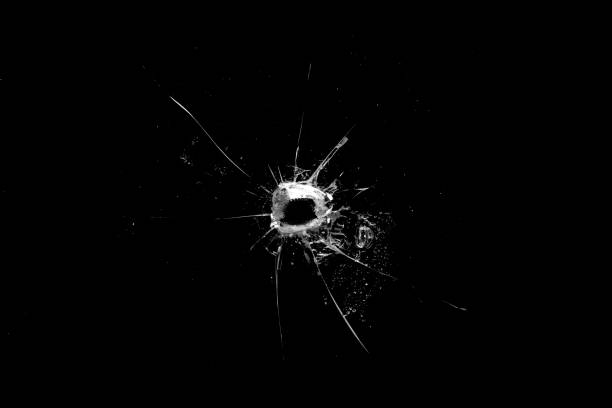 istock hole in the glass with cracks isolated on a black background 1194573353