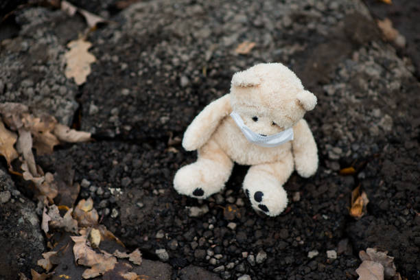 istock a teddy bear in a medical mask sits on dirty ground 1194573376