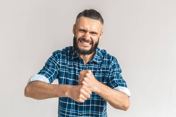 istock Freestyle. Guy in checkered shirt standing isolated on white making fists strangling gesture frowning showing teeth furious 1194573689
