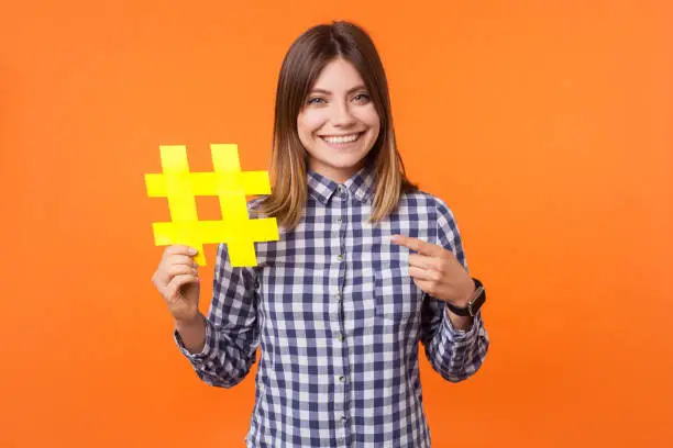 Photo of Media trending and blogging. Portrait of young happy brunette woman with charming smile. isolated on orange background