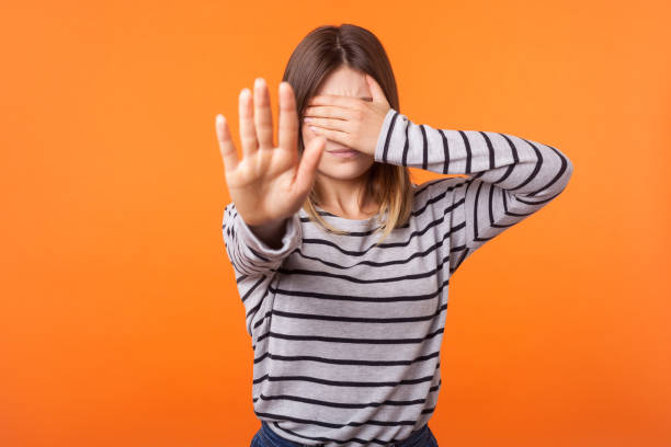 No! I don't want to see this. Portrait of shocked woman with brown hair in long sleeve shirt. isolated on orange background No! I don't want to see this. Portrait of shocked woman with brown hair in long sleeve shirt standing covering eyes with arm and showing stop gesture. indoor studio shot isolated on orange background Phobia stock pictures, royalty-free photos & images