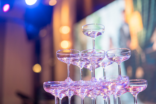 Cocktail glasses tower in wedding banquet with purple light and blurred light bulbs