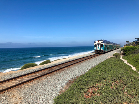 Amtrak Pacific Surfliner train with blue ocean and blue sky, passing by Del Mar, San Diego. USA.