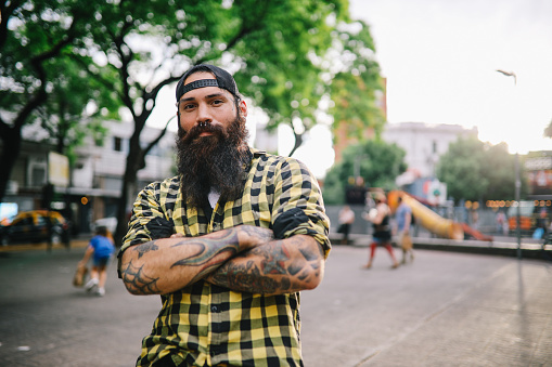 Bearded tattooed young man standing and posing in the streets of Buenos Aires, Argentina.