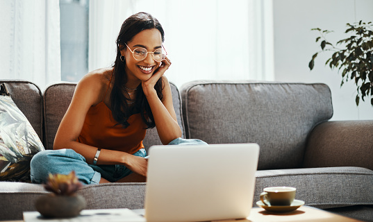 Shot of a young woman using a laptop on the sofa at home