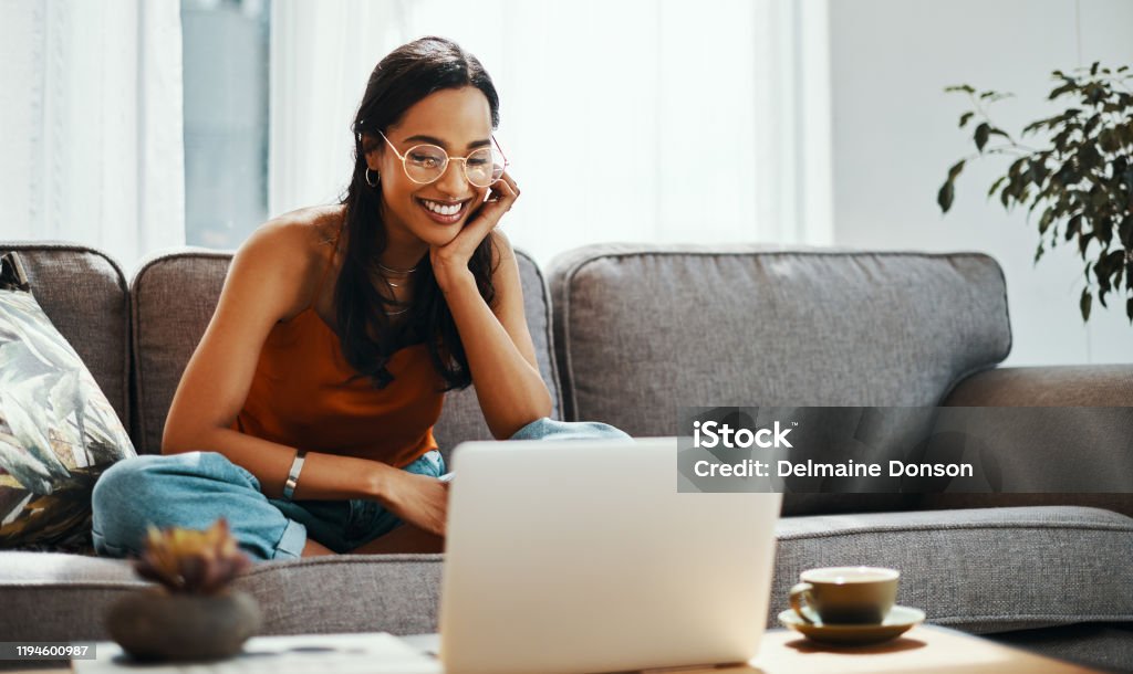 Sofa time is for movie marathons Shot of a young woman using a laptop on the sofa at home Laptop Stock Photo