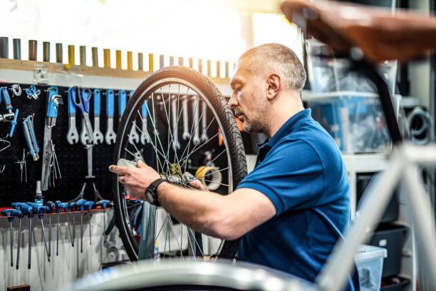 istock Bicycle mechanic repairing a bicycle wheel in workshop. 1194602961