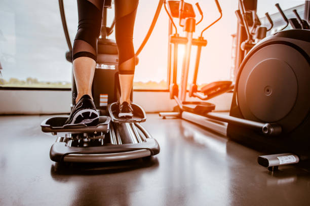 Closeup leg of cardio workout on an elliptical.people working out on an elliptical trainer in gym.Back view stock photo