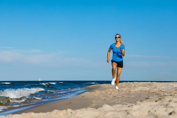 istock Young woman running on beach 1194609695