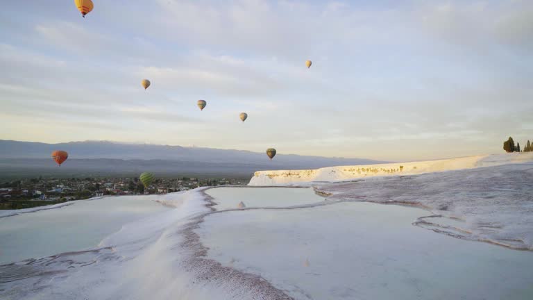 Hot air balloons in travertine pools limestone terraces at sunrise in Pamukkale, Denizli