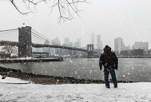 Man standing at Brooklyn Bridge Park and watching the view of lower Manhattan