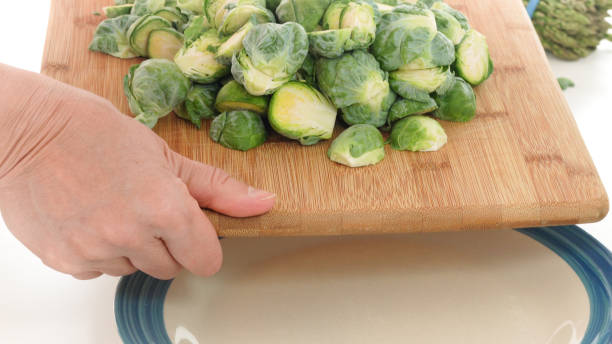 istock Woman puts Brussels sprouts off cutting board on a plate 1194619921