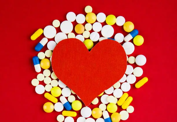 Heart Shape with a Pills on the Red Paper Background