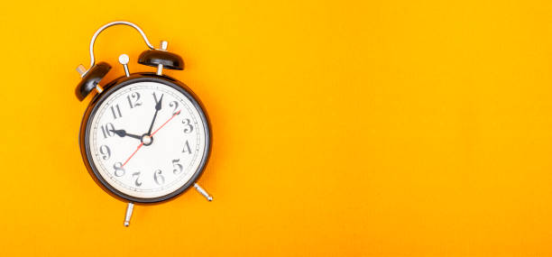 istock Vintage style alarm clock on yellow background banner with copy space 1194622104