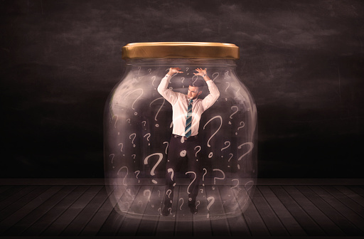 Businessman locked into a jar with question marks concept on background