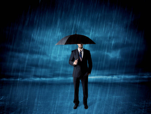 istock Business man standing in rain with an umbrella 1194623713