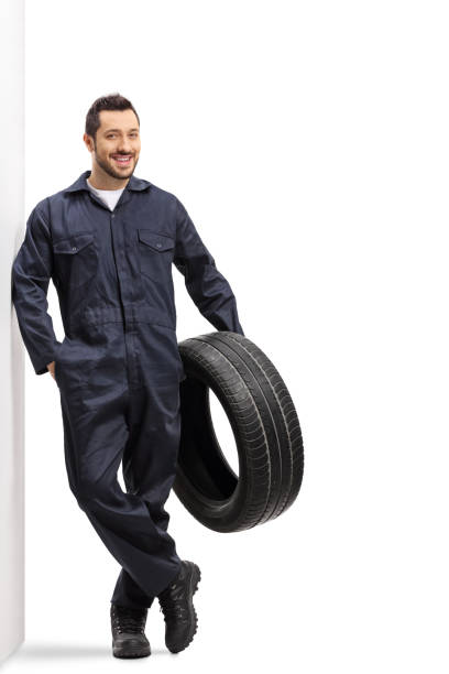 istock Auto mechanic holding a tire and leaning on a wall 1194626680