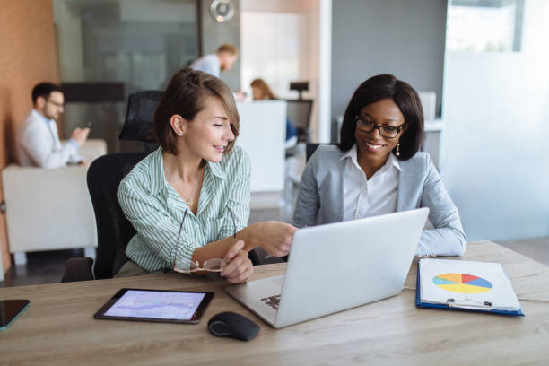 istock Businesswomen with laptop, digital tablet and chart papers cooperating 1194627582