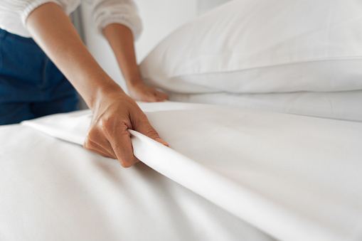 Mano femenina configurar sábana blanca en el dormitorio photo