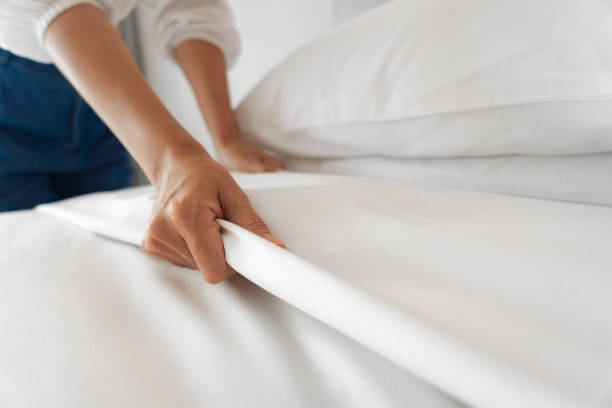 mano femenina configurar sábana blanca en el dormitorio - hotel fotografías e imágenes de stock