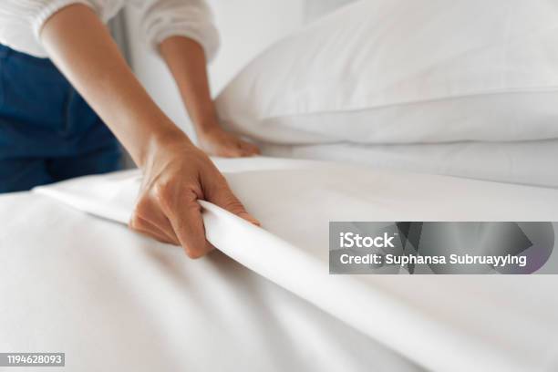 Vrouwelijke Hand Instellen Wit Bed Blad In De Slaapkamer Stockfoto en meer beelden van Bed