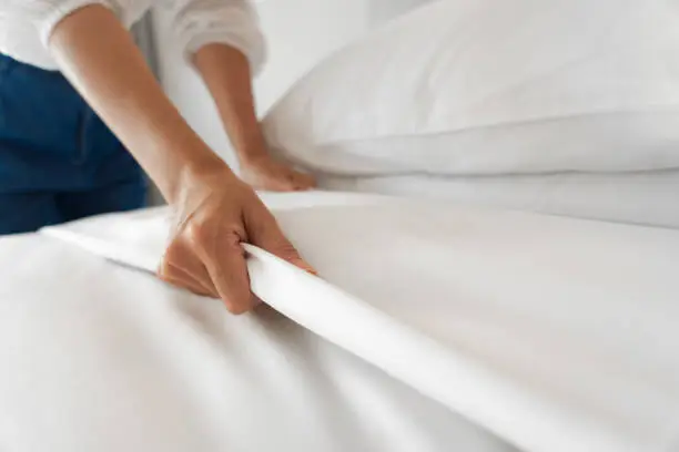 Photo of Female Hand set up white bed sheet in bedroom