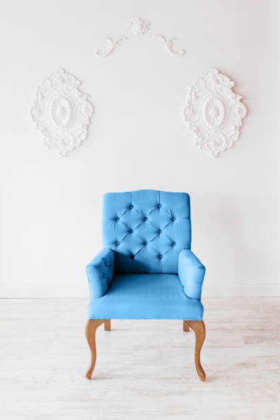 istock Classic blue chair on white wall background with swirl decorations. Studio interior. 1194633146