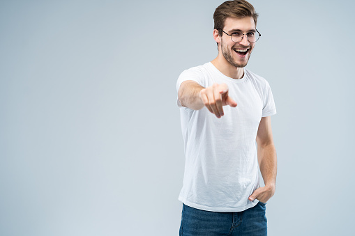 Smiling man pointing his finger to you over gray background