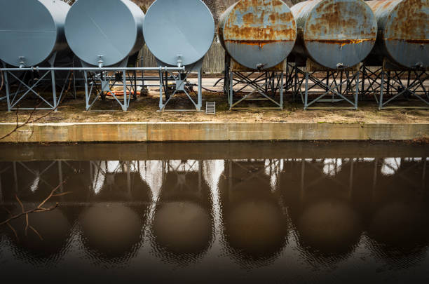Reflections of rustic round metal tanks on water surface