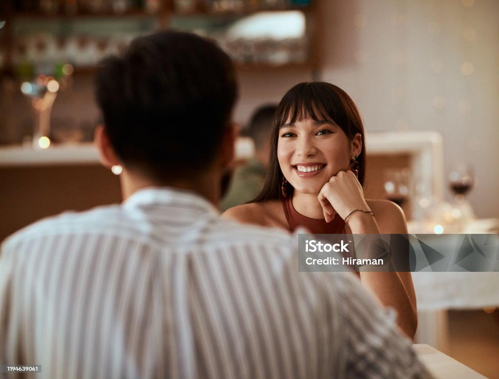 You can tell that she's falling for him Cropped shot of a young woman smiling while on a date at a restaurant Dating Stock Photo