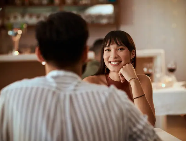 Cropped shot of a young woman smiling while on a date at a restaurant