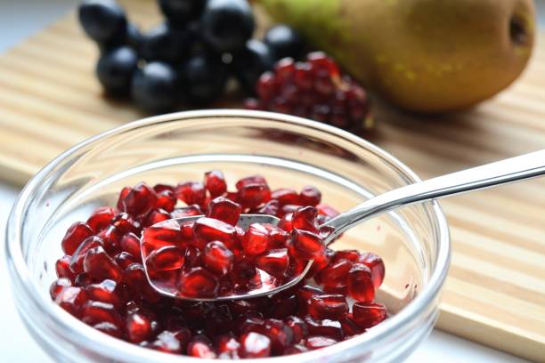 istock Red pomegranate grains on a plate and fruits 1194640714