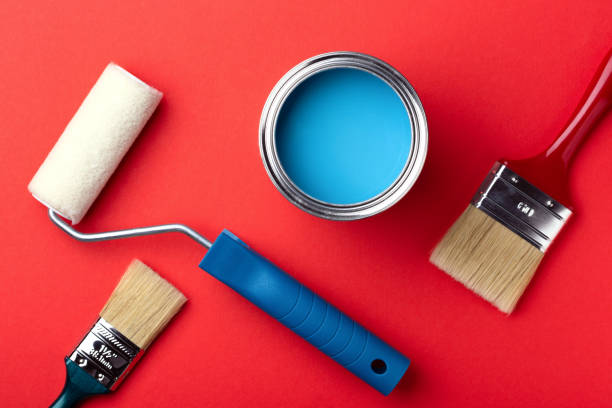 istock Can of blue paint, paint roller and brushes on red. 1194641987