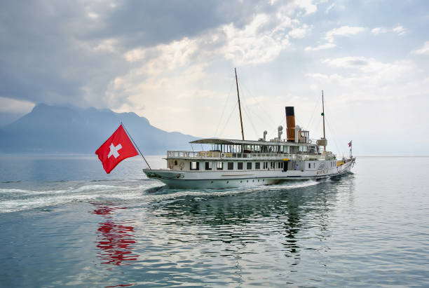 un navire blanc, un navire avec le drapeau suisse flotte sur un lac miroir de genève. - lake geneva photos et images de collection