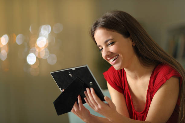 Happy woman remembering good times looking at picture frame