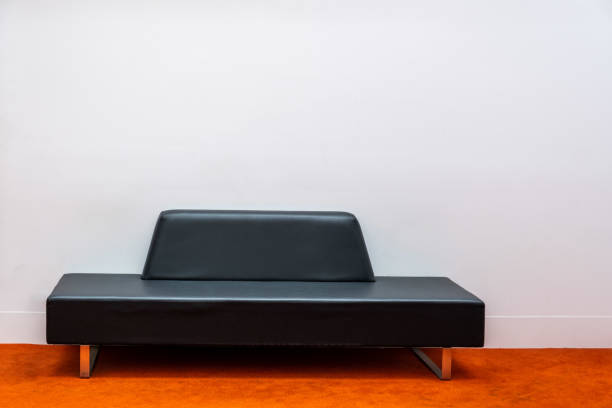 istock Modern minimalist black couch on orange carpet against white wall with copy space 1194647429
